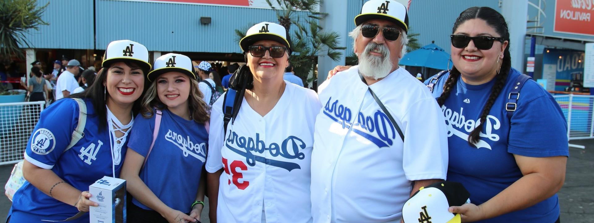 Five people posing with Cal State LA baseball caps at Dodger Stadium